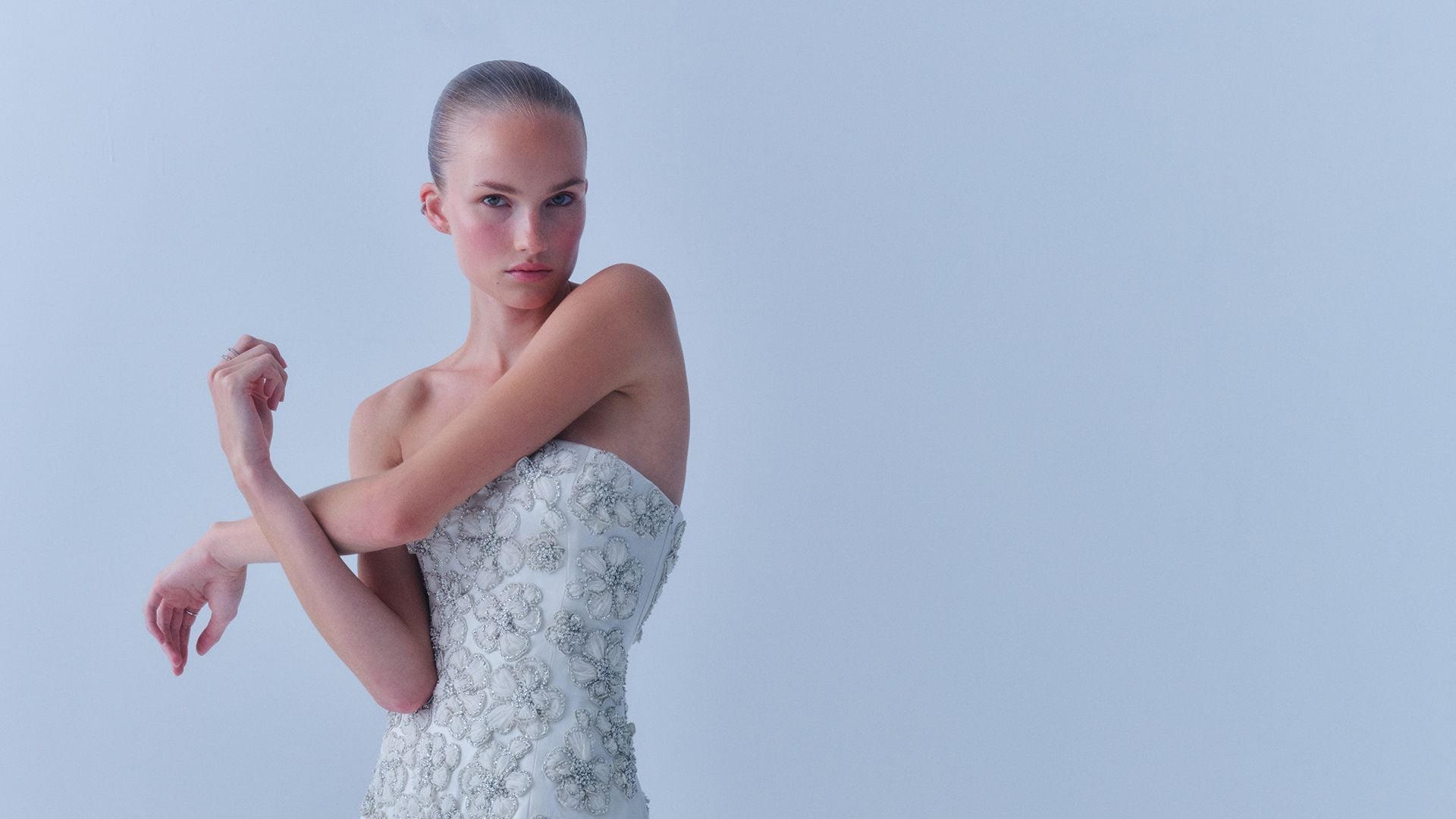 Model wearing a Danarys New York couture bridal weekend mini gown with embellished detailing and a dramatic back train.